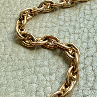 18k gold antique watch chain on a textured light green surface