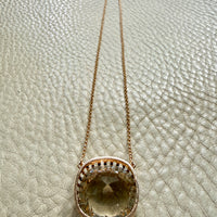 Gold necklace with a pendant on a textured beige surface