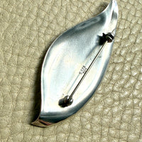 Silver brooch on a textured beige surface