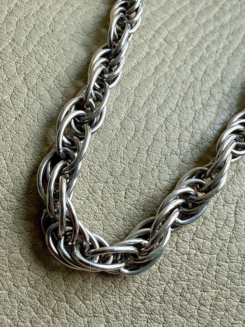 Silver chain necklace on a textured beige surface