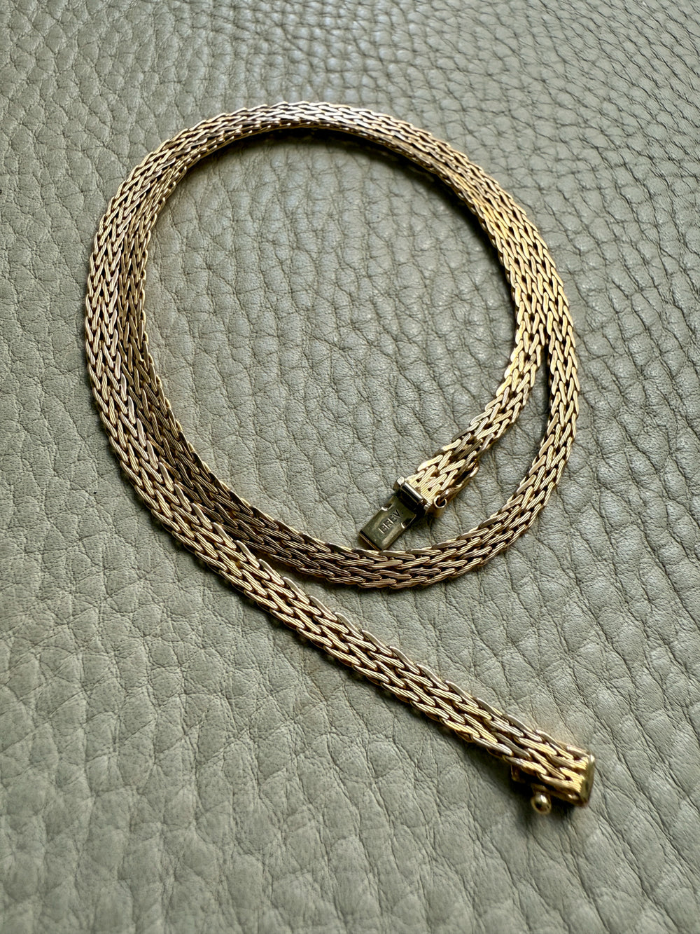 Gold chain necklace on a textured gray surface