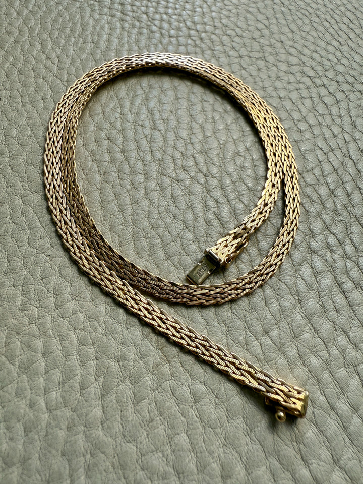Gold chain necklace on a textured gray surface