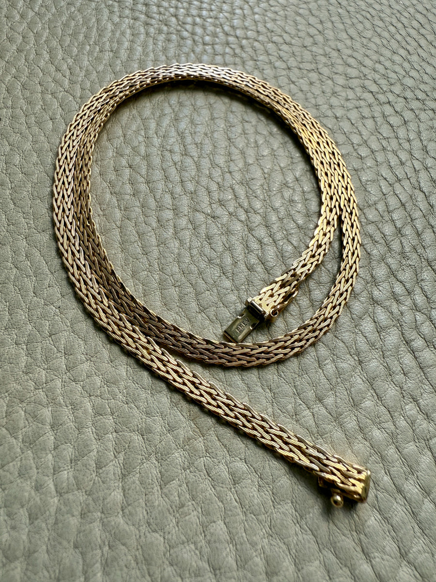 Gold chain necklace on a textured gray surface