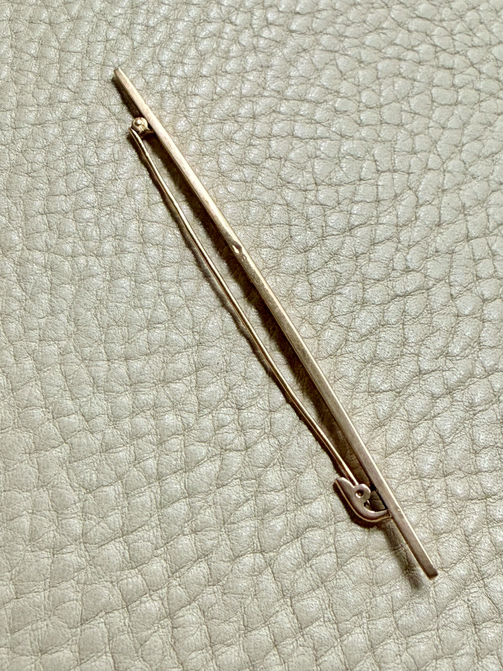 18k gold antique brooch on a textured beige background