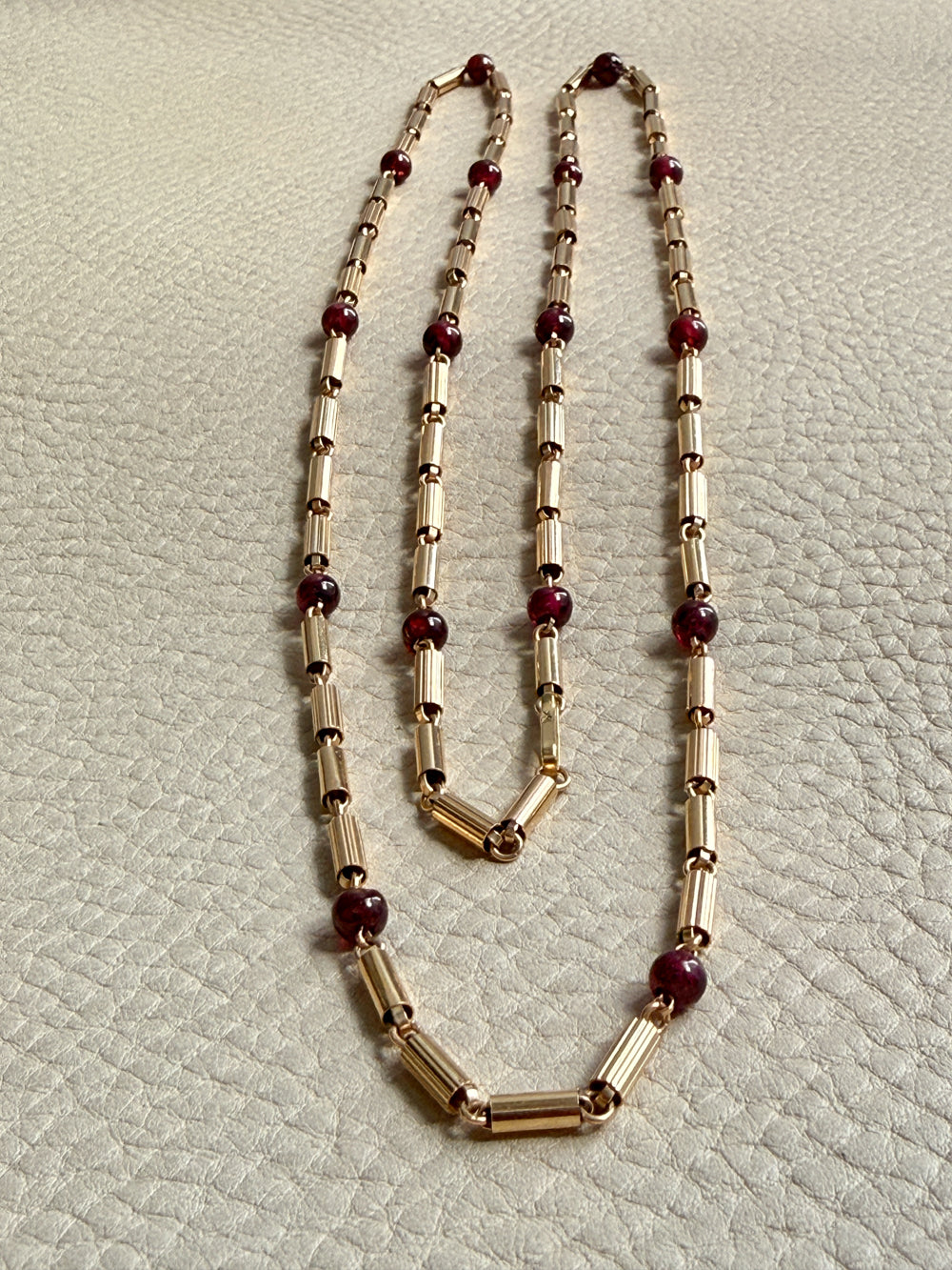 18k gold Necklace with gold and red beads on a textured light gray background