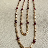 18k gold Necklace with gold and red beads on a textured light gray background