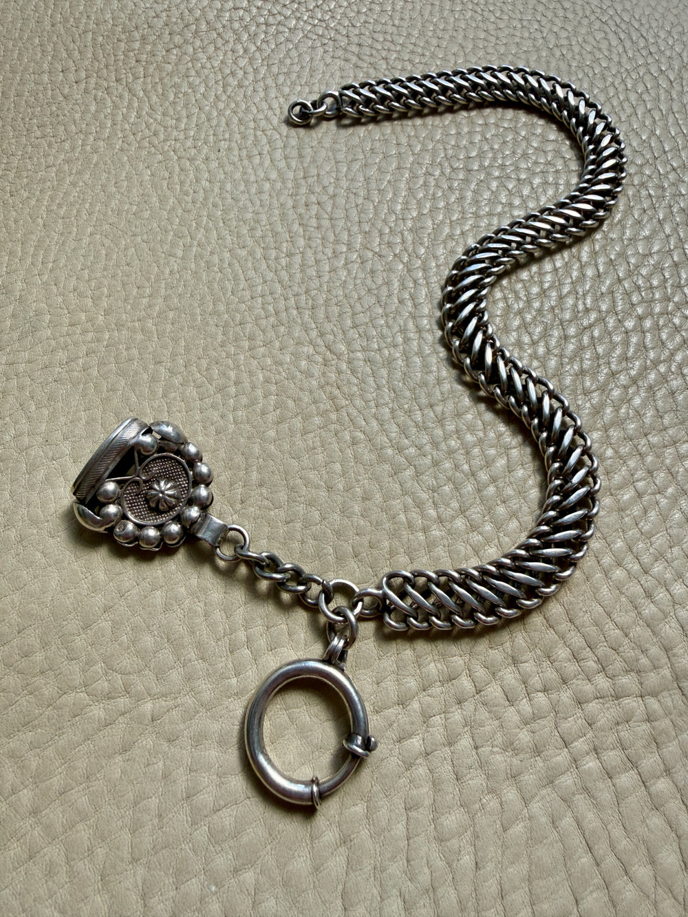 antique Silver watch chain with large bolt clasp on a textured beige surface