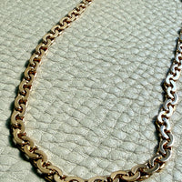 Gold chain necklace on a textured light green surface