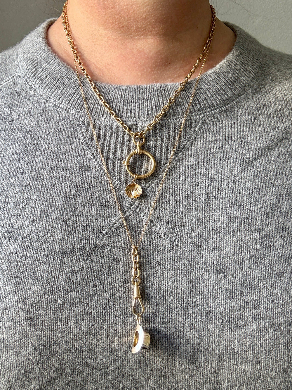 Gold necklaces with pendants on a gray sweater