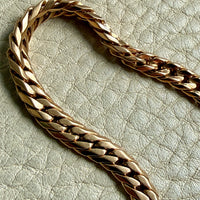 18k vintage Gold curb chain bracelet on a textured light gray surface penelopepenelope.com