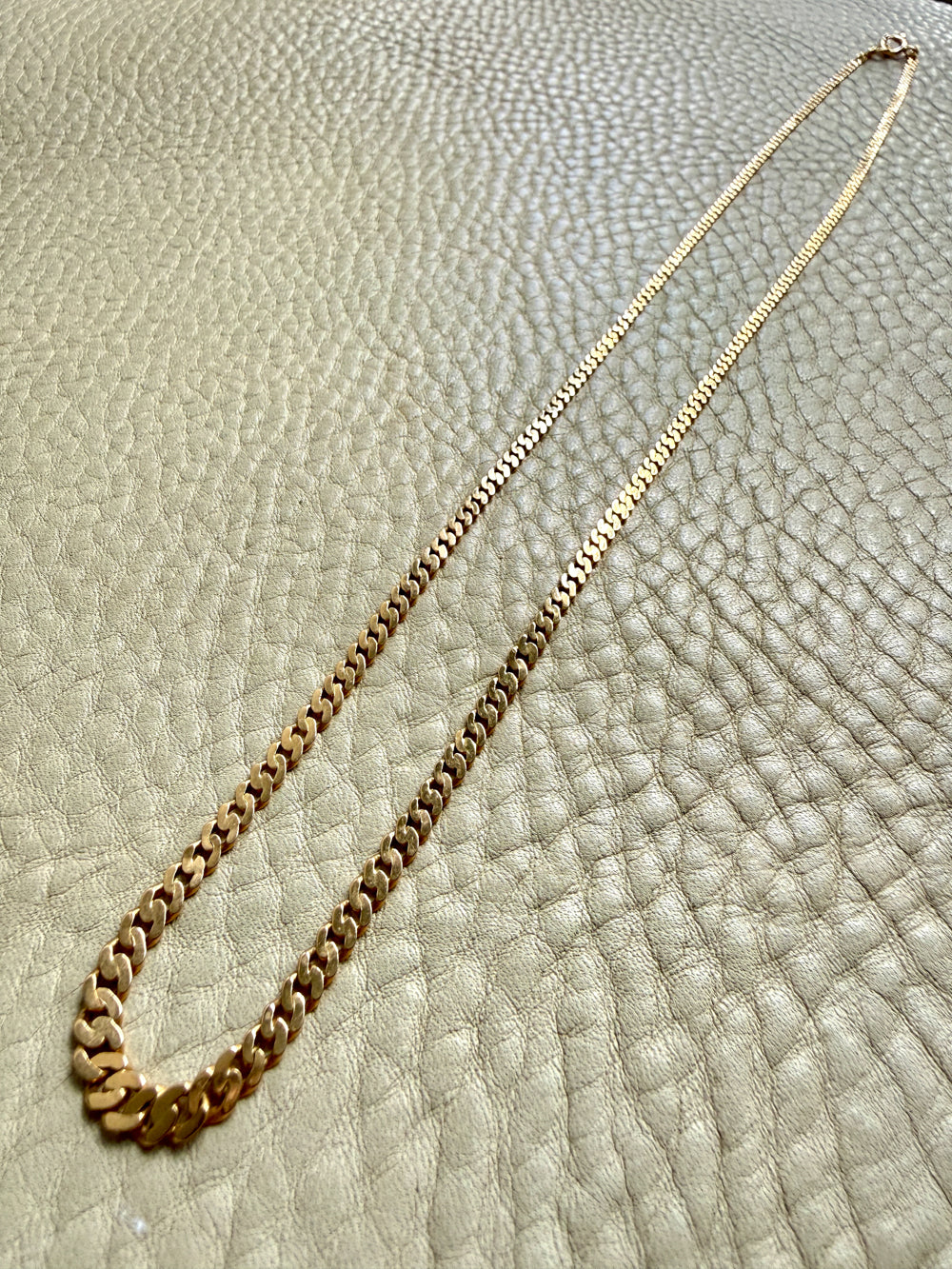 Gold chain necklace on a textured beige surface