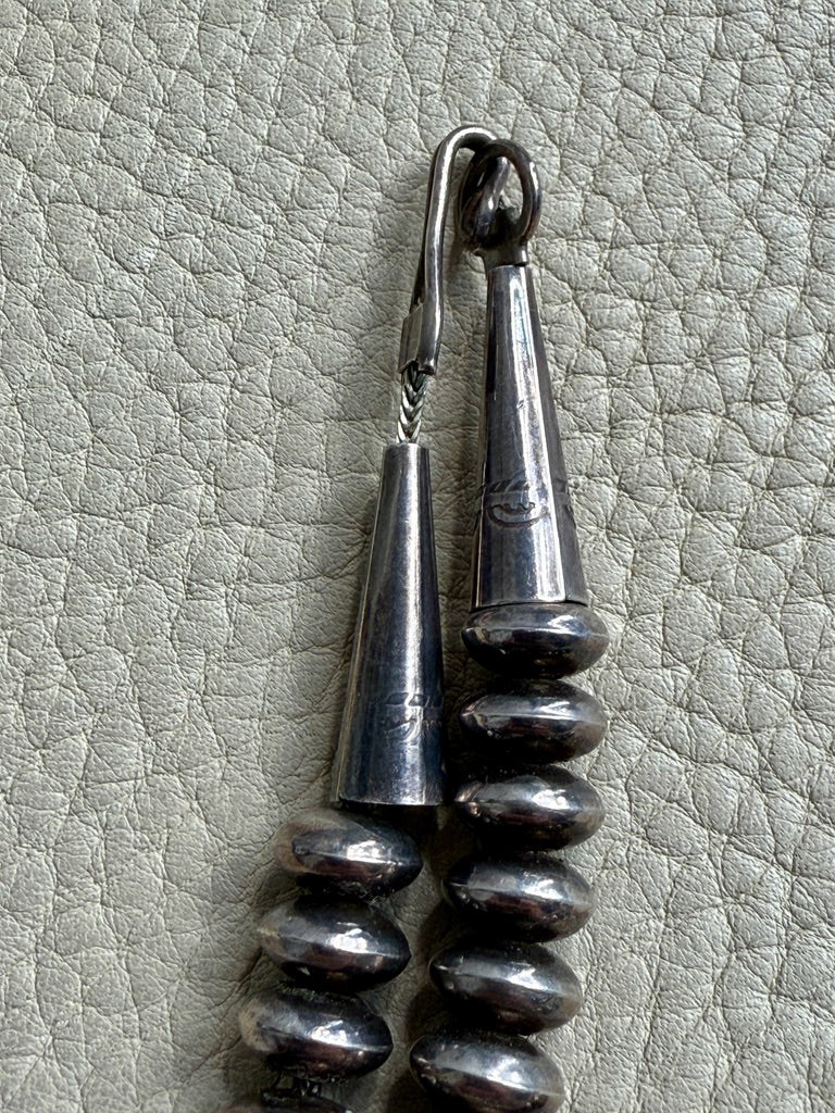 Silver necklace clasp on a textured gray surface