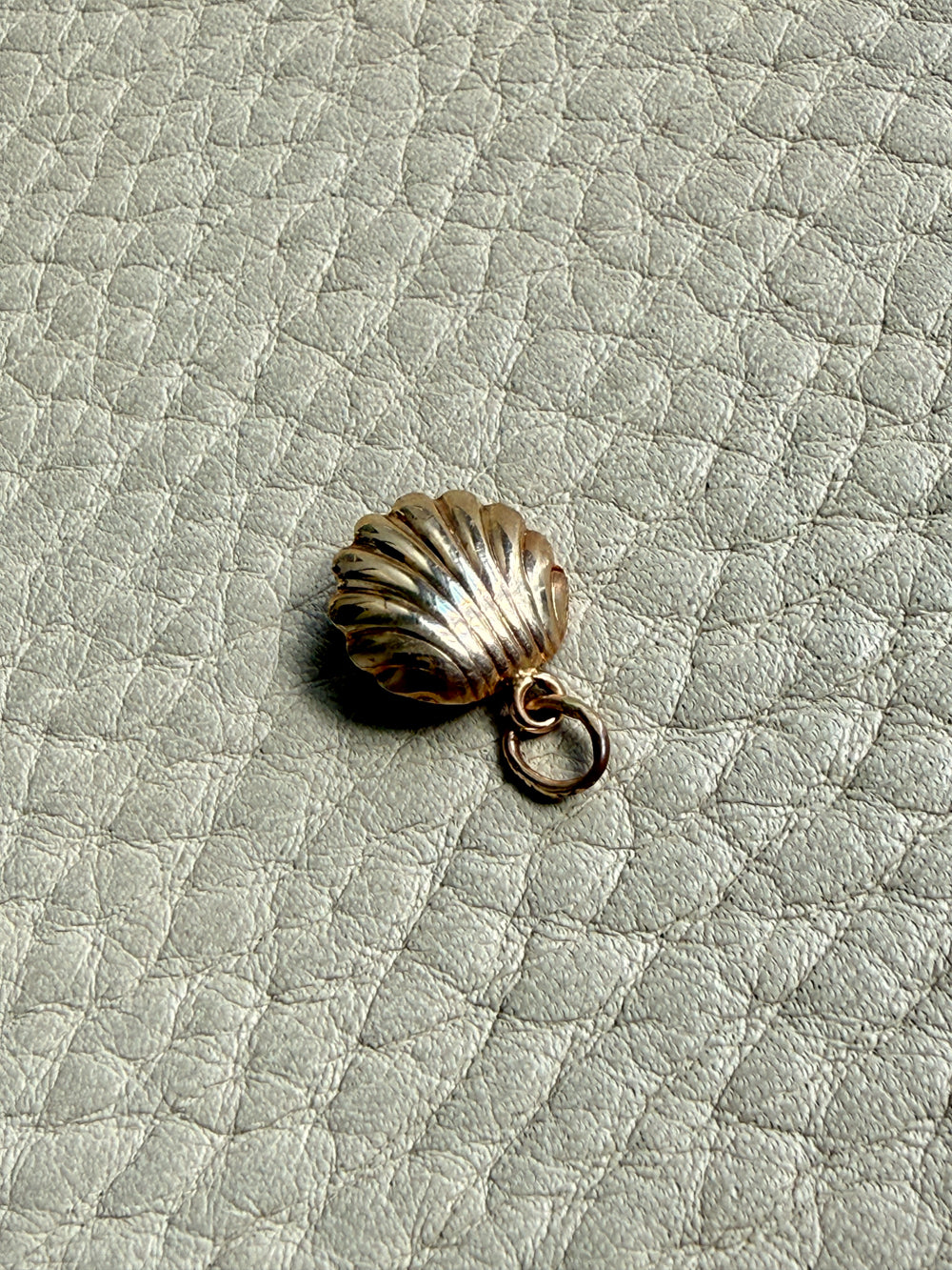vintage 14k Gold shell charm with a pearl on a textured beige background