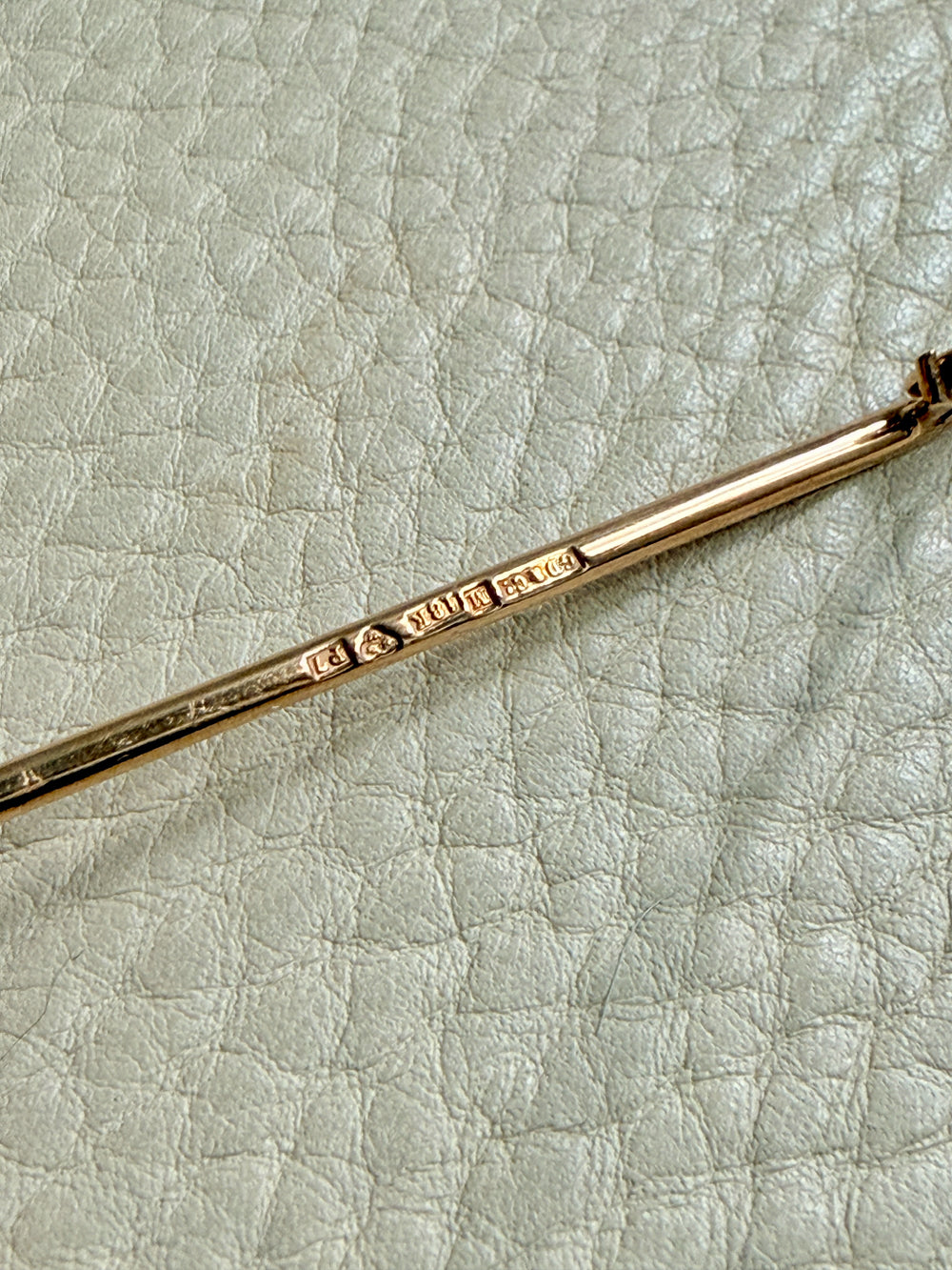 Gold brooch detail on a textured light gray surface