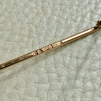 Gold brooch detail on a textured light gray surface