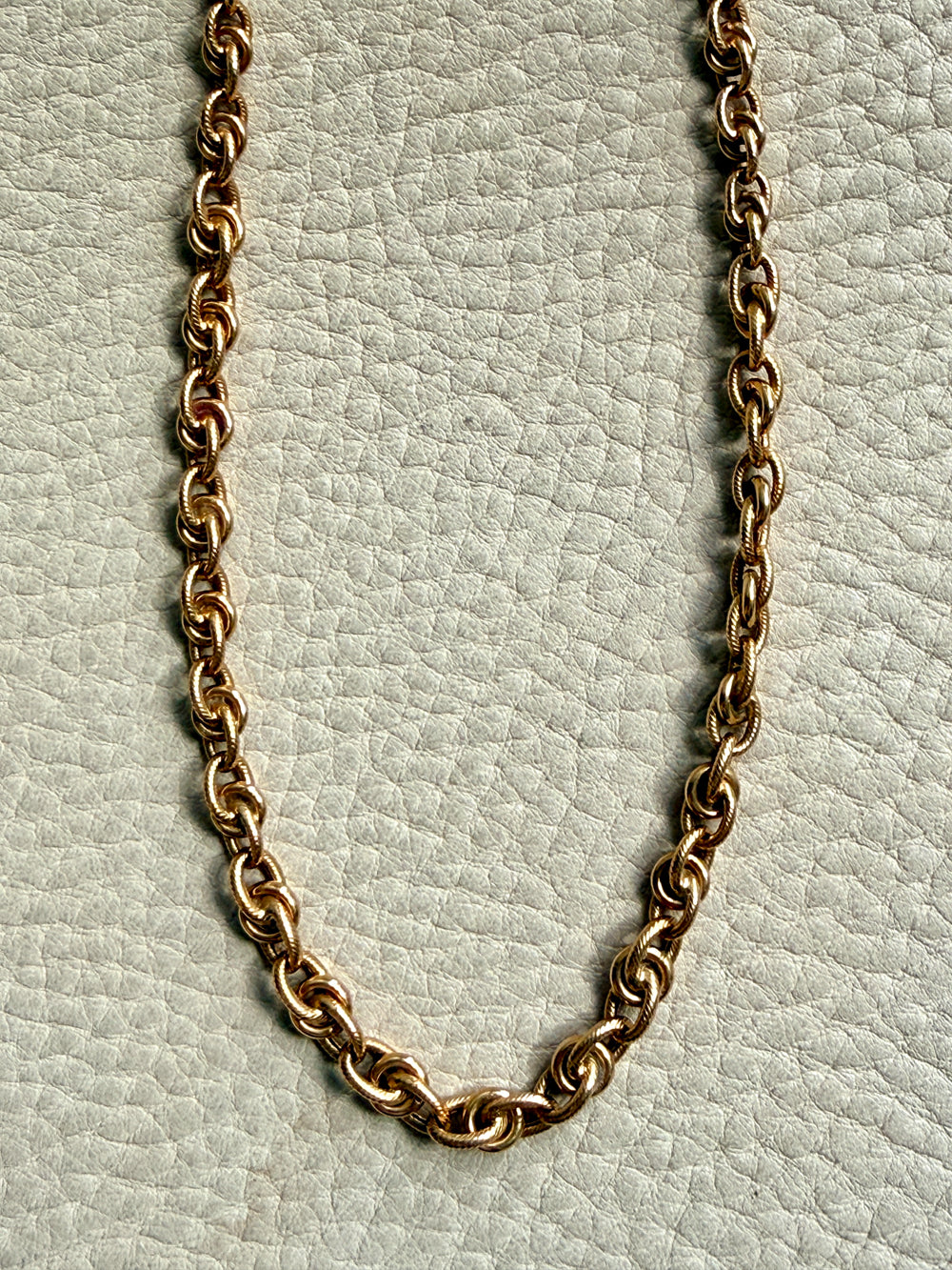 Gold chain necklace on a light gray textured background