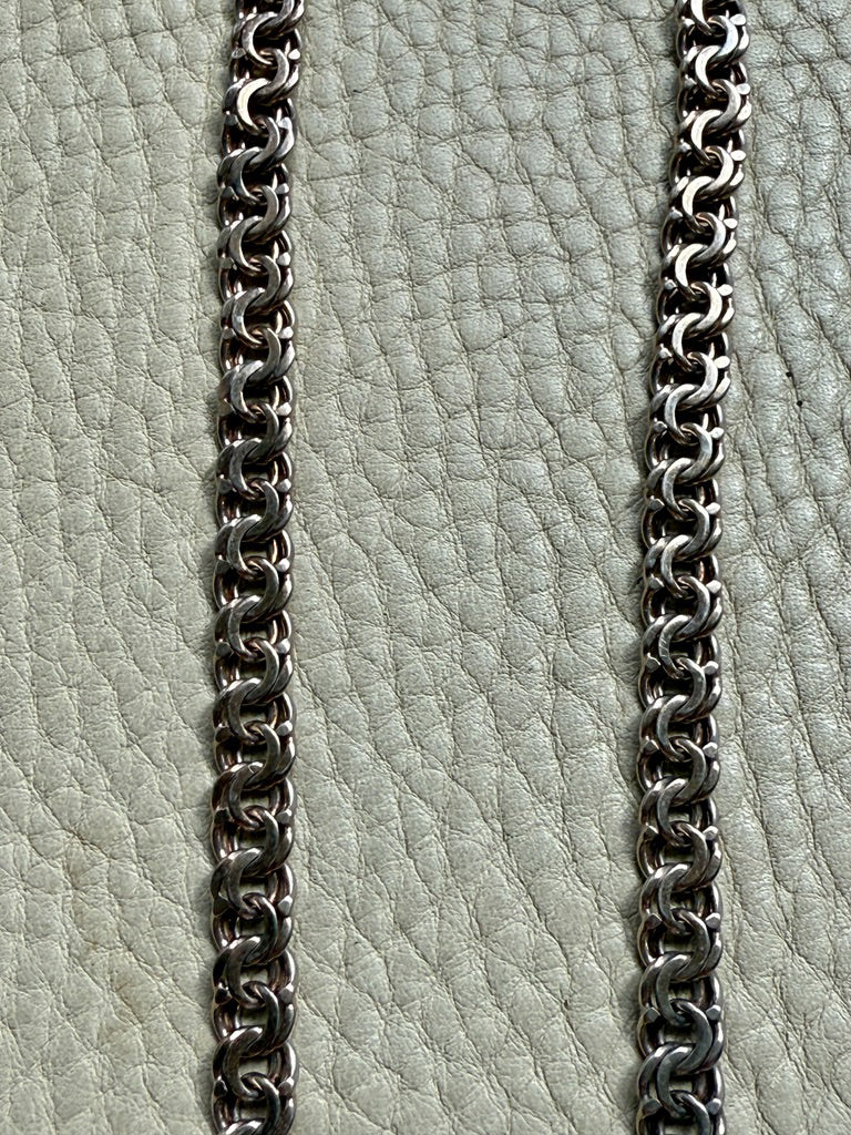 Close-up of a chain on a textured light green surface