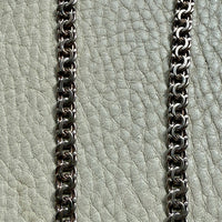 Close-up of a chain on a textured light green surface