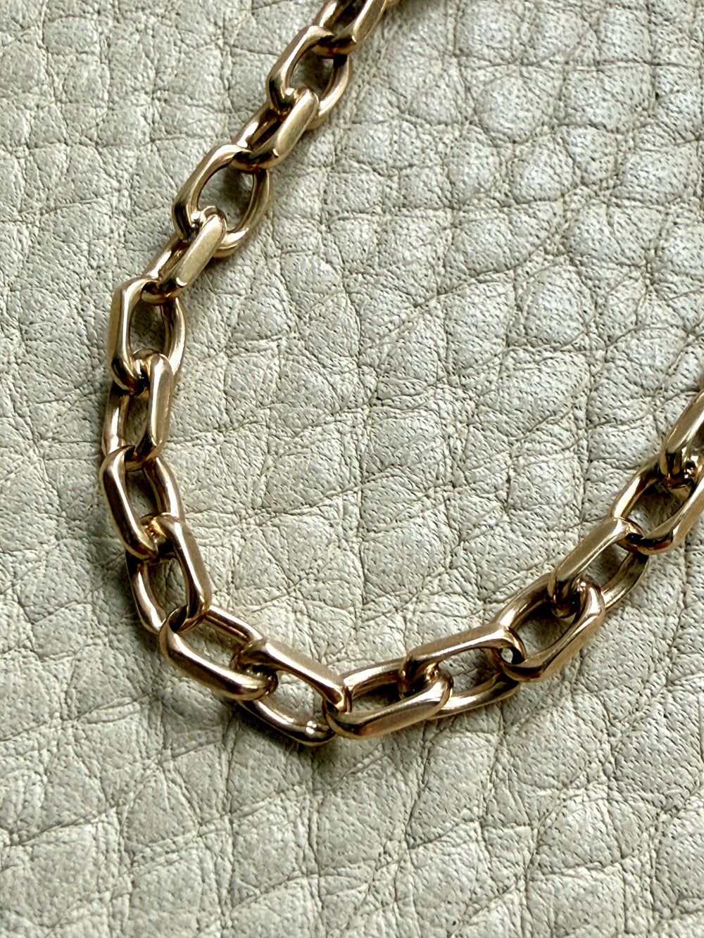 14k Gold vintage biker chain bracelet on a textured light gray background