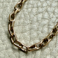 14k Gold vintage biker chain bracelet on a textured light gray background