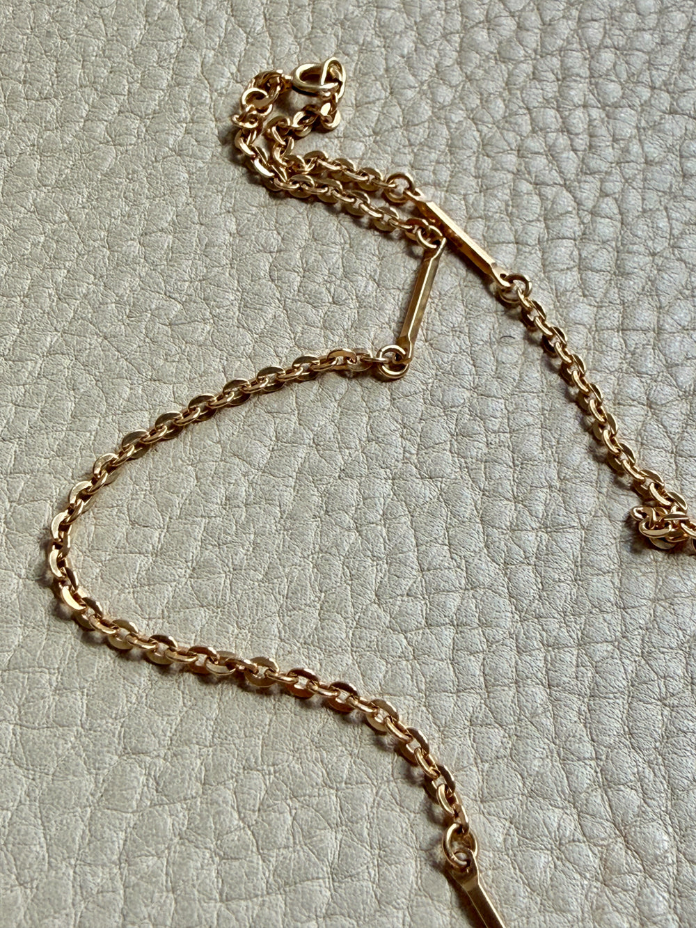 Gold chain necklace on a textured light gray background