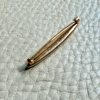 14k Gold brooch on a textured light blue surface