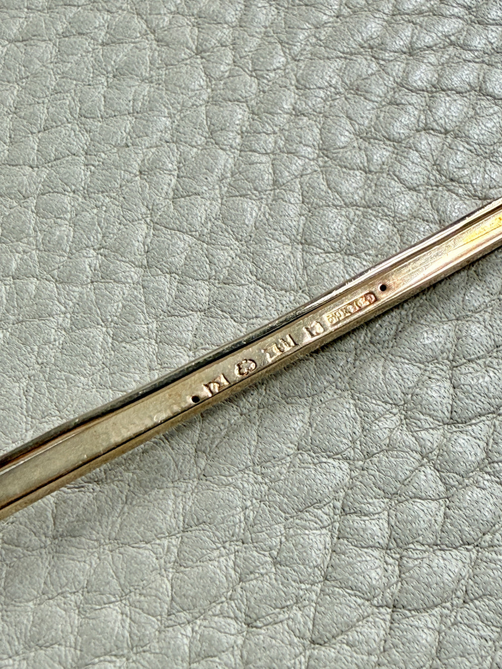 Close-up of a 18k gold antique brooch on a textured beige background