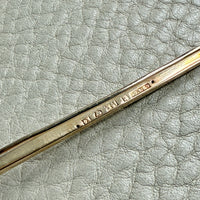 Close-up of a 18k gold antique brooch on a textured beige background