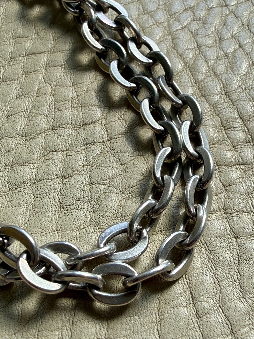 Close-up of a silver chain on a textured beige surface