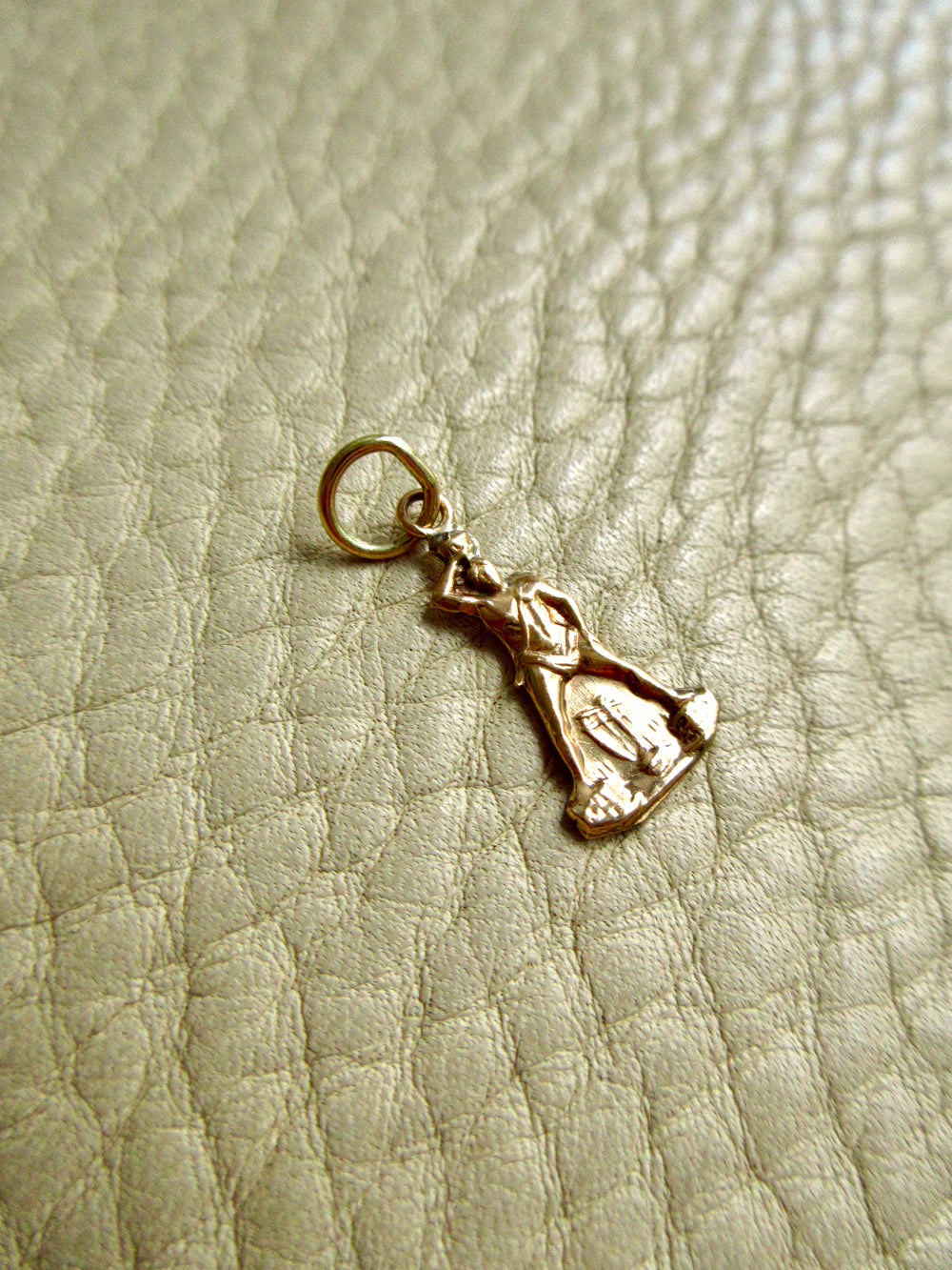 18k gold vintage charm on a beige leather surface penelopepenelope.com