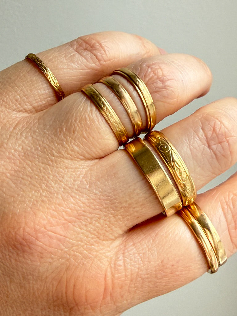 vintage and antique 18k Gold rings on a hand against a neutral background