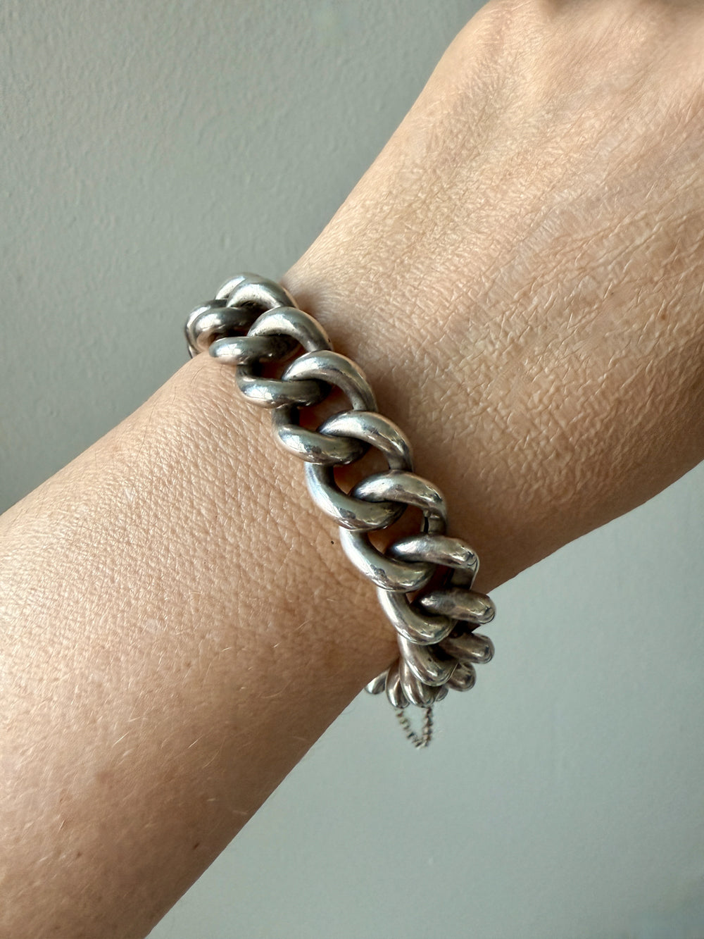 Silver chain bracelet on a wrist against a neutral background