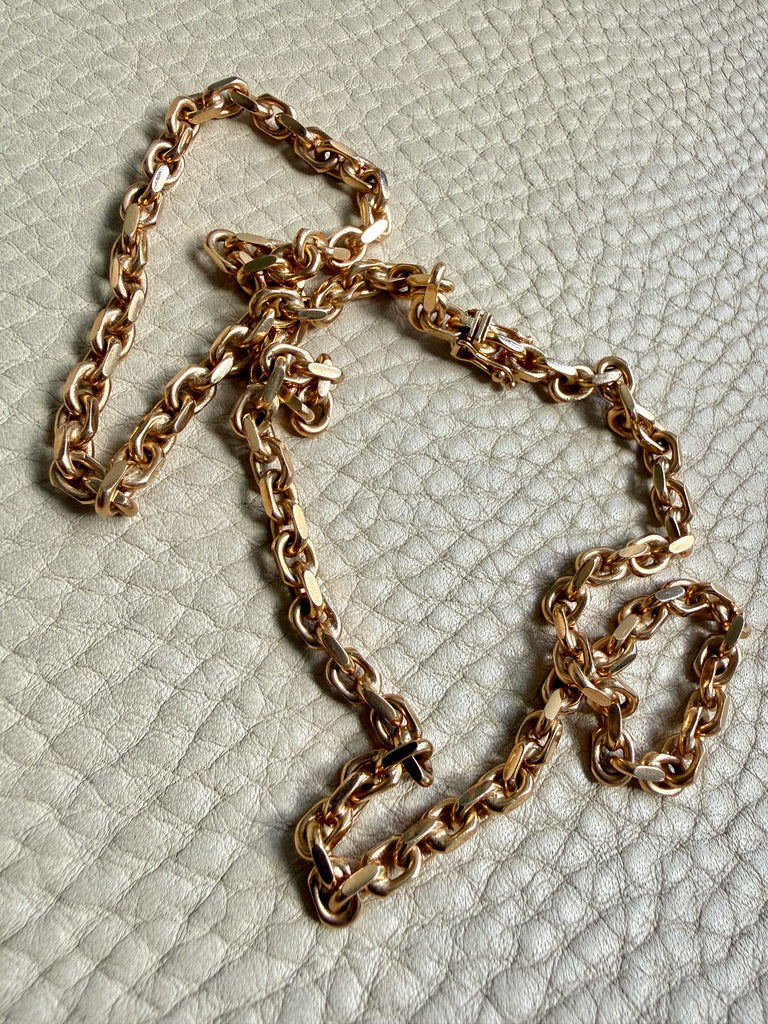 18k Gold chain biker link on a textured light gray background