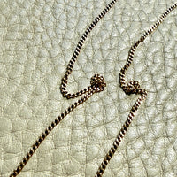 Gold chain necklace on a textured beige surface