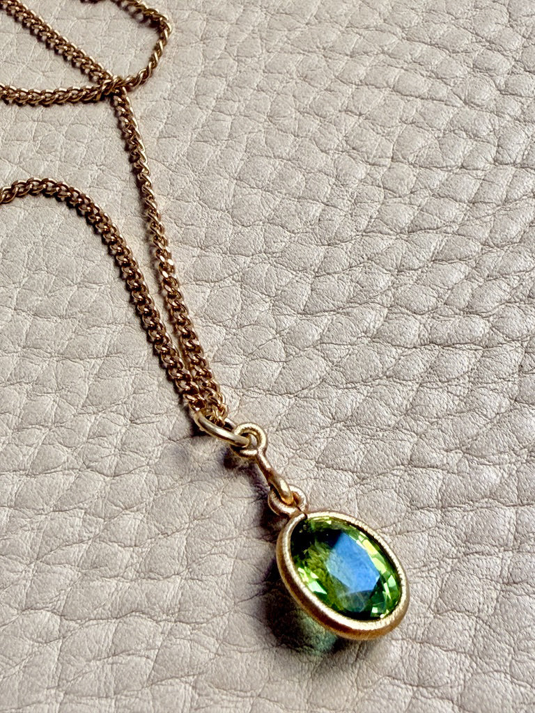 Necklace with a green gemstone pendant on a textured surface