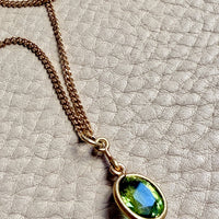 Necklace with a green gemstone pendant on a textured surface