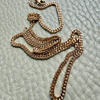 18k Gold curb chain necklace on a textured light surface