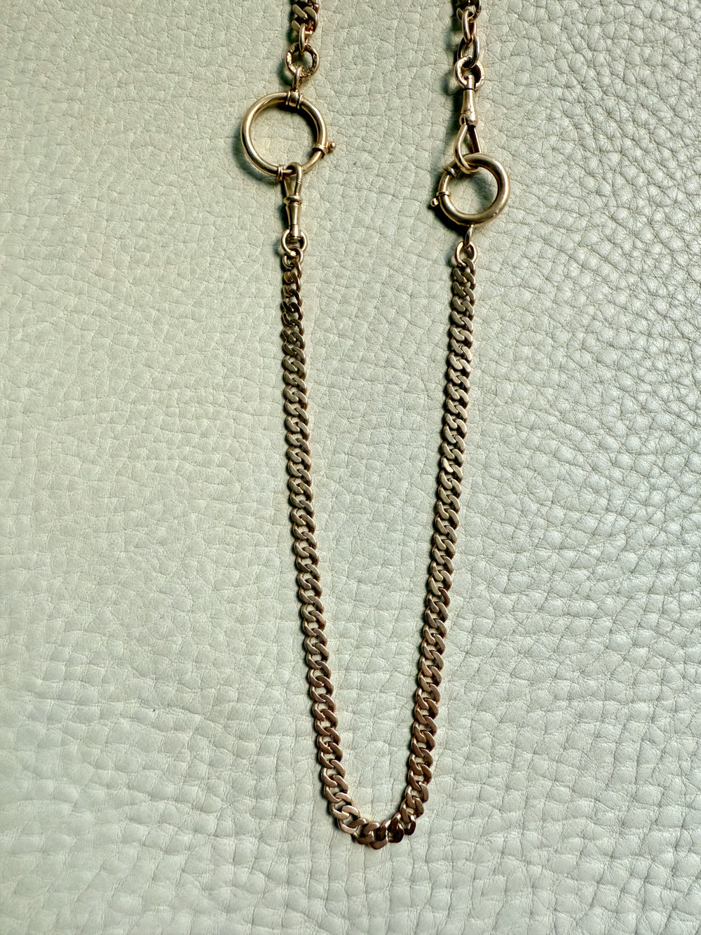 Gold chain necklace on a textured light green background