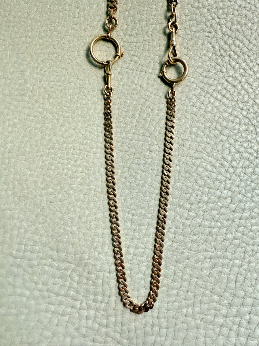 Gold chain necklace on a textured light green background