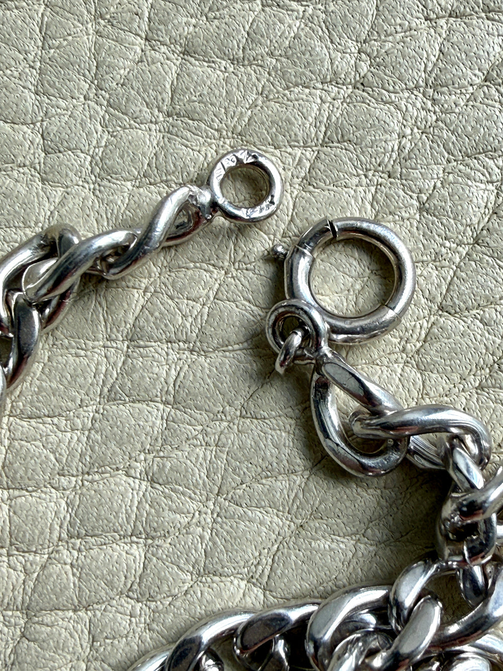 Close-up of a vintage 14k white gold chain  on a textured beige surface