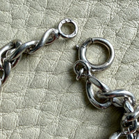 Close-up of a vintage 14k white gold chain  on a textured beige surface