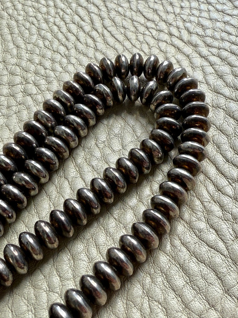 Coiled metal beaded necklace on a textured surface