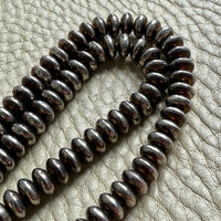 Coiled metal beaded necklace on a textured surface