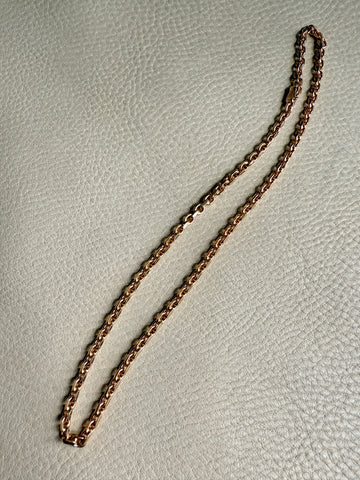 Gold chain necklace on a light gray background