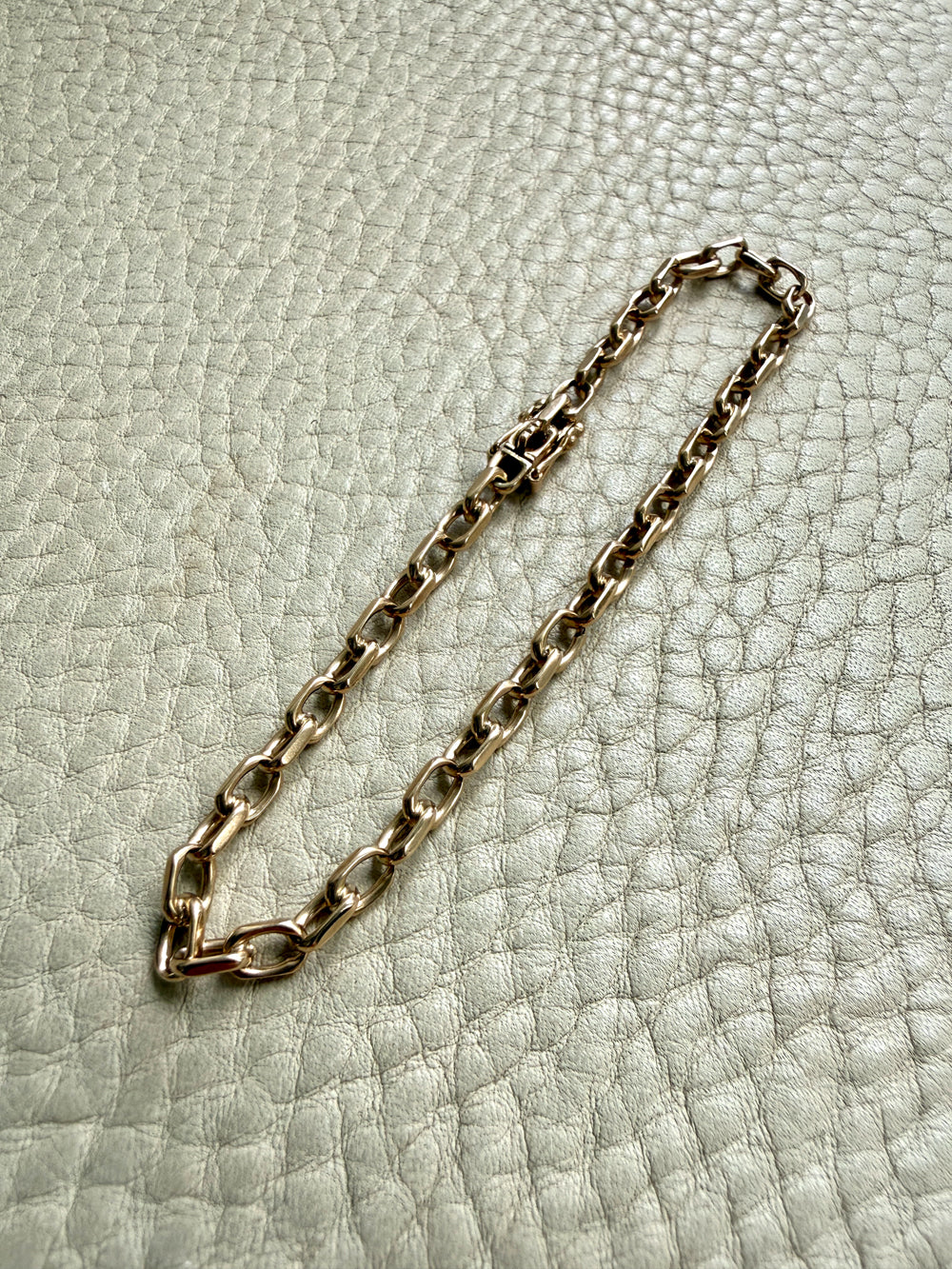 14k Gold vintage biker chain bracelet on a textured light gray background