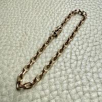 14k Gold vintage biker chain bracelet on a textured light gray background