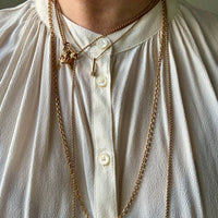 Person wearing a gold chain necklace on a light-colored shirt.