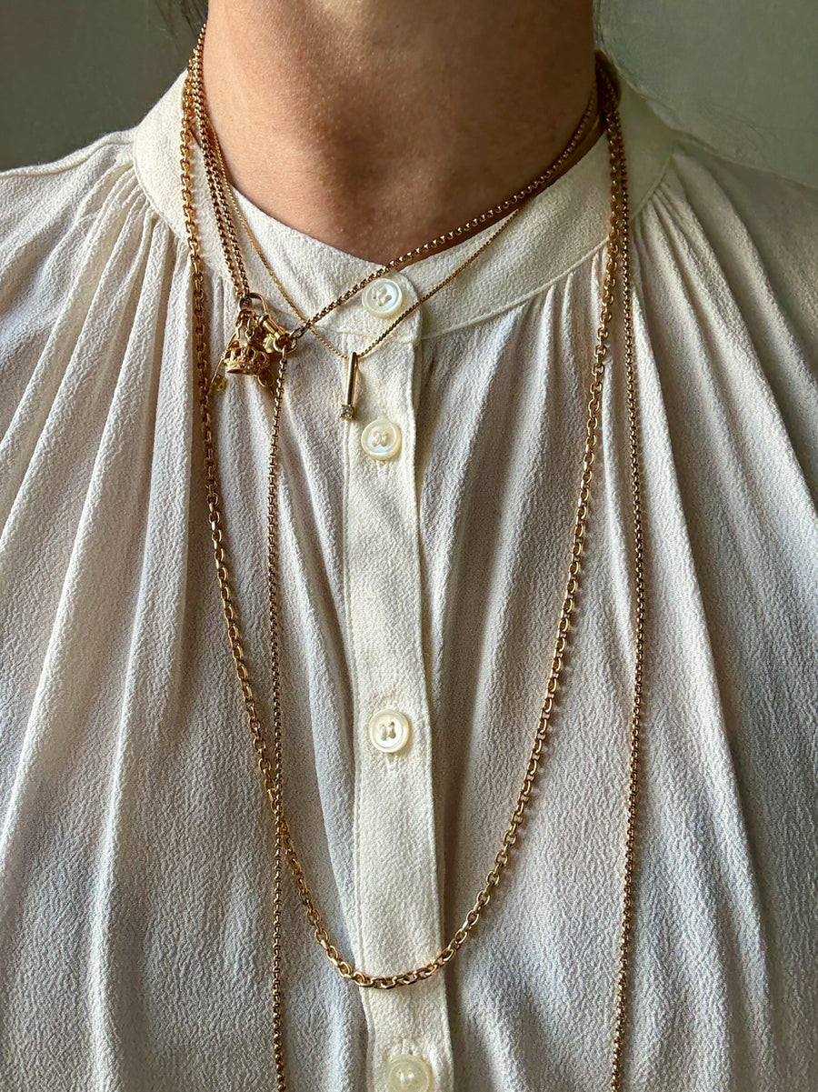 Person wearing a gold chain necklace on a light-colored shirt.