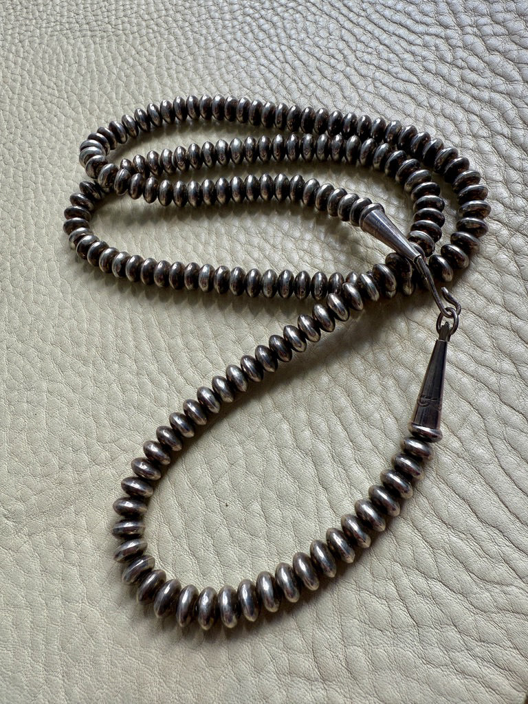 Silver beaded necklace on a textured surface