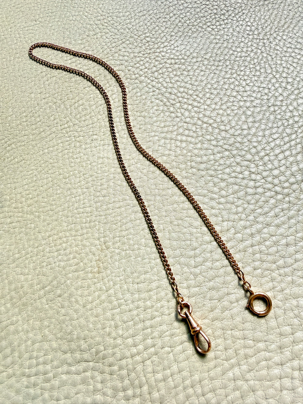 Gold chain necklace on a textured light green background